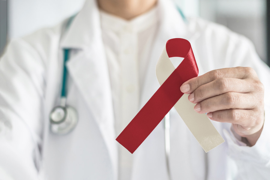 closeup of a dentist in white holding a red and cream ribbon to symbolize oral cancer awareness, dentist in Hot Springs Village