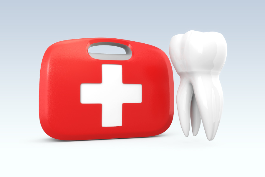 A white tooth next to a red and white first aid kit for a dental emergency