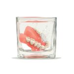 dentures soaking in glass of denture cleaner for denture care